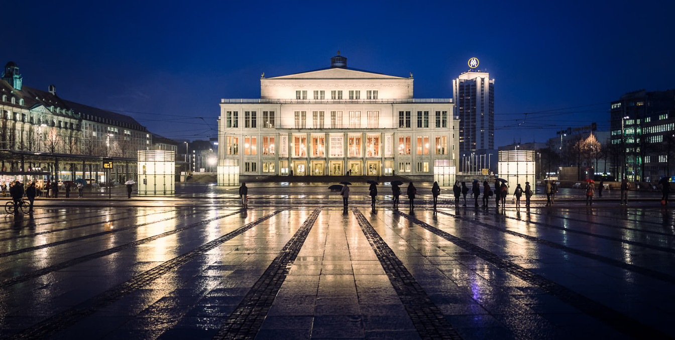 Blick auf die beleuchtete Oper Leipzig mit Spiegelungen der Lichter auf dem nassen Boden des Augustusplatz die eine wahre Sehenswürdigkeit der Musikstadt Leipzig ist, Kultureinrichtung, Veranstaltungen
