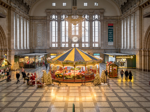 Blick auf die weihnachtlich geschmückte Westhalle des Hauptbahnhofs Leipzig, wo ein großes Karussel für Kinder steht, Shopping, Freizeit, Kinder, Familie
