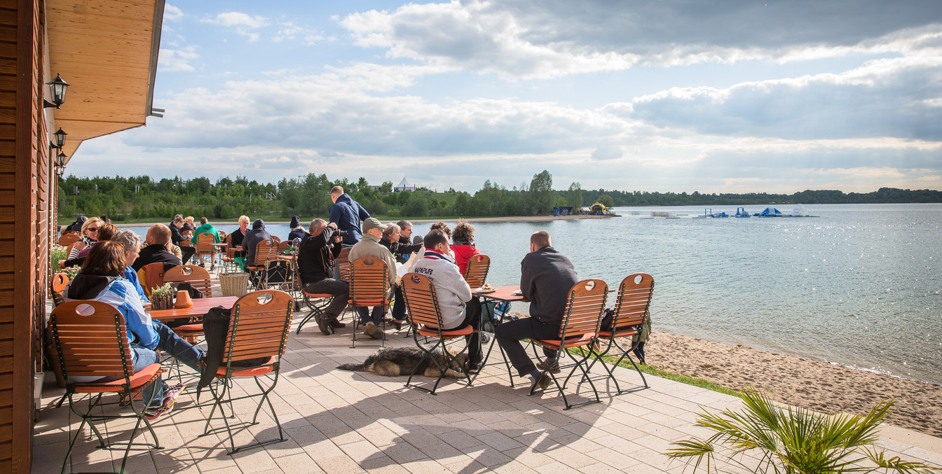 Auf der Terrasse des Restaurants Levante sitzen Gäste und genießen den einen weitläufigen Blick auf den Schladitzer See, Leipziger Neuseenland, gastronomie-restaurant