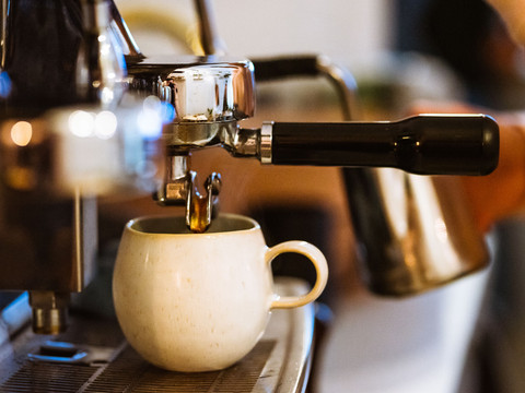 Eine Kaffeetasse steht unter einer Siebträgermaschine im Roots Pflanzencafé, gastronomie, kaffee