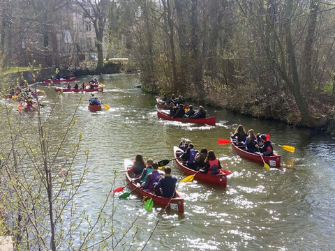 zahlreiche Personen paddeln in roten Kanus auf den Kanälen der Stadt Leipzig, Wassersport in Leipzig